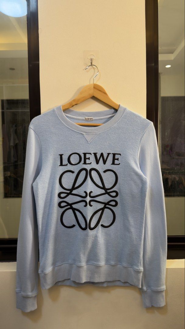 Loewe Light Blue Anagram Sweatshirt (Category: Coats, Jackets and Outerwear) located in Paranaque City. Submitted by preluxeshop_ph (Listing ID 1467296889, Image 2). Description: Loewe Light Blue Anagram Sweatshirt - Style: Crewneck sweatshirt - Color: Light blue with black Anagram logo - Material: 100% cotton - Origin: Made in Portugal - Size: S - Condition/Details: Comfortable fit with ribbed collar, cuffs, and hem.
