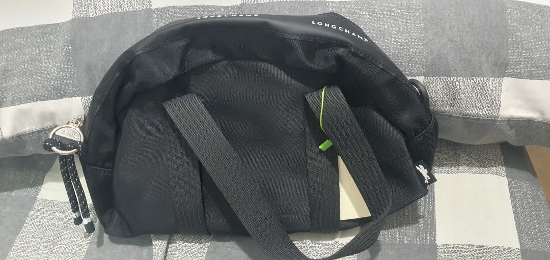 Longchamp Black Crossbody Bag (Category: Luxury Bags & Wallets) located in Paranaque City. Submitted by personal_preloved40 (Listing ID 1467258921, Image 2). Description: Black Longchamp crossbody bag, solid nylon material. Zip top closure with rope pull and printed brand logo around the rim. Dual carry handles plus adjustable strap tucked inside. Includes internal pockets and attached tag. Never used, stored in original plastic packaging..