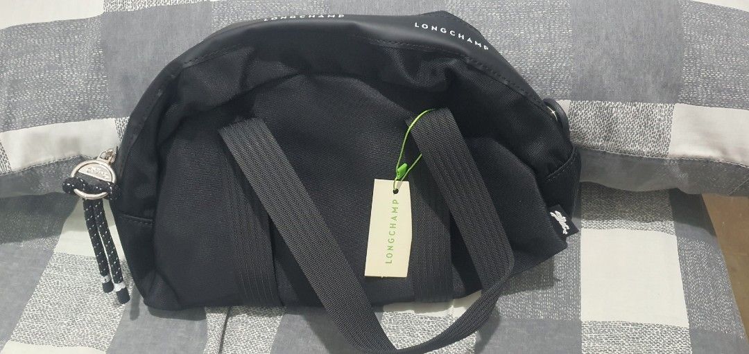Longchamp Black Crossbody Bag (Category: Luxury Bags & Wallets) located in Paranaque City. Submitted by personal_preloved40 (Listing ID 1467258921, Image 3). Description: Black Longchamp crossbody bag, solid nylon material. Zip top closure with rope pull and printed brand logo around the rim. Dual carry handles plus adjustable strap tucked inside. Includes internal pockets and attached tag. Never used, stored in original plastic packaging..