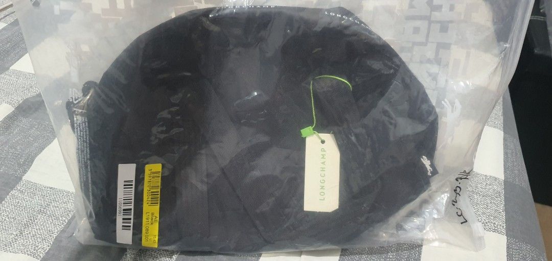 Longchamp Black Crossbody Bag (Category: Luxury Bags & Wallets) located in Paranaque City. Submitted by personal_preloved40 (Listing ID 1467258921, Image 1). Description: Black Longchamp crossbody bag, solid nylon material. Zip top closure with rope pull and printed brand logo around the rim. Dual carry handles plus adjustable strap tucked inside. Includes internal pockets and attached tag. Never used, stored in original plastic packaging..