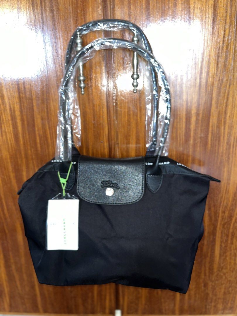 Longchamp Black Tote Bag with Top Handles (Category: Tote Bags) located in Lucena. Submitted by unnieskollegsyeononlineshop (Listing ID 1467315876, Image 1). Description: - Color: Classic Black - Condition: Brand new, handles still in original plastic packaging with brand tag attached - Closure: Leather flap snap closure and secure zippered top with a pull cord - Exterior: Longchamp lettering printed along the upper fabric trim - Interior: Clean 