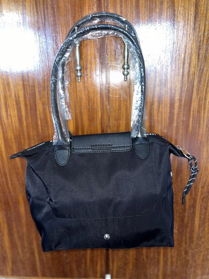 Longchamp Black Tote Bag with Top Handles (Category: Tote Bags) located in Lucena. Submitted by unnieskollegsyeononlineshop (Listing ID 1467315876, Image 2). Description: - Color: Classic Black - Condition: Brand new, handles still in original plastic packaging with brand tag attached - Closure: Leather flap snap closure and secure zippered top with a pull cord - Exterior: Longchamp lettering printed along the upper fabric trim - Interior: Clean 