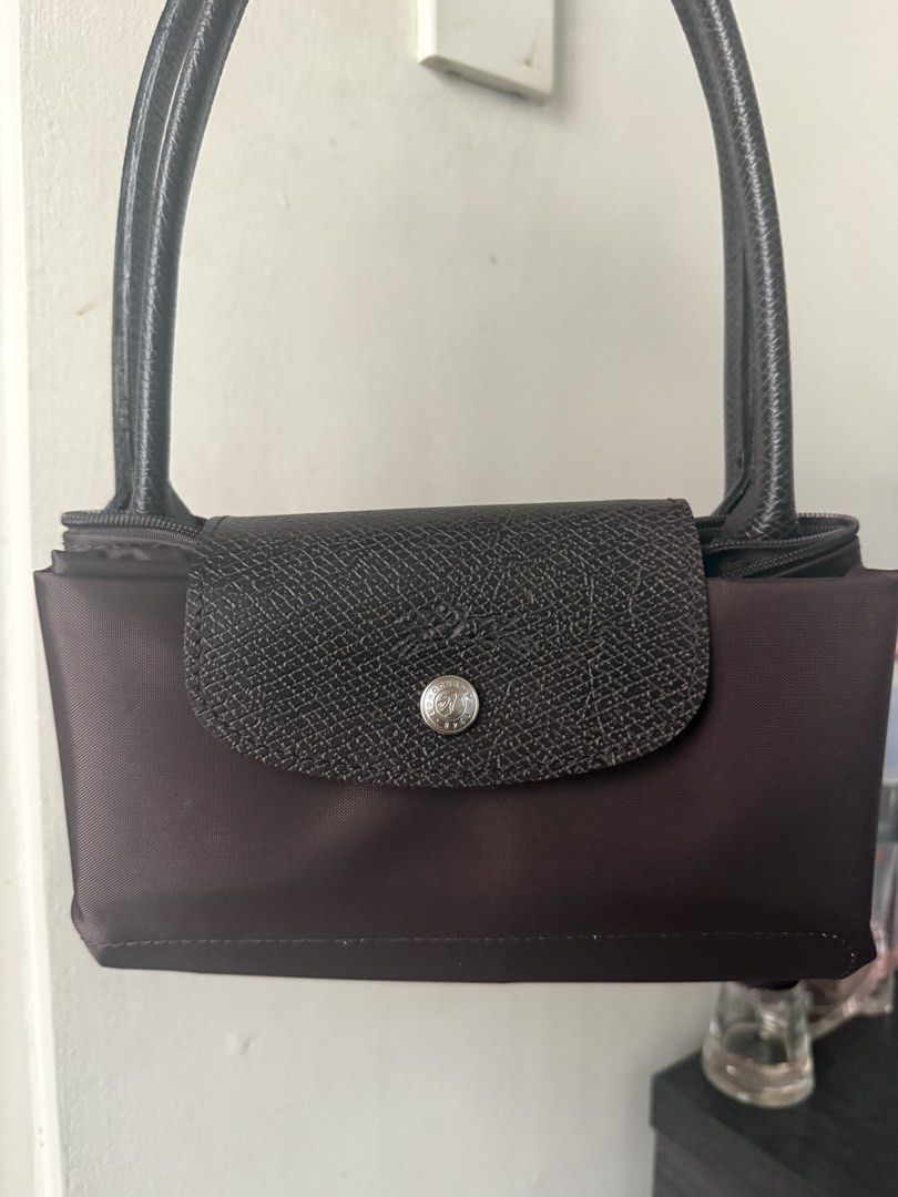 Longchamp Le Pliage Moka Brown Bag (Category: Luxury Bags & Wallets) located in Quezon City. Submitted by msaisa (Listing ID 1467184345, Image 2). Description: - Brand: Longchamp Le Pliage - Color: Moka (Brown) - Condition: Brand new with store tag, still inside original clear plastic packaging - Design: Compact size with double shoulder handles, top zip closure, and iconic front snap button flap - Style: Versatile and chic everyday shoulder bag.