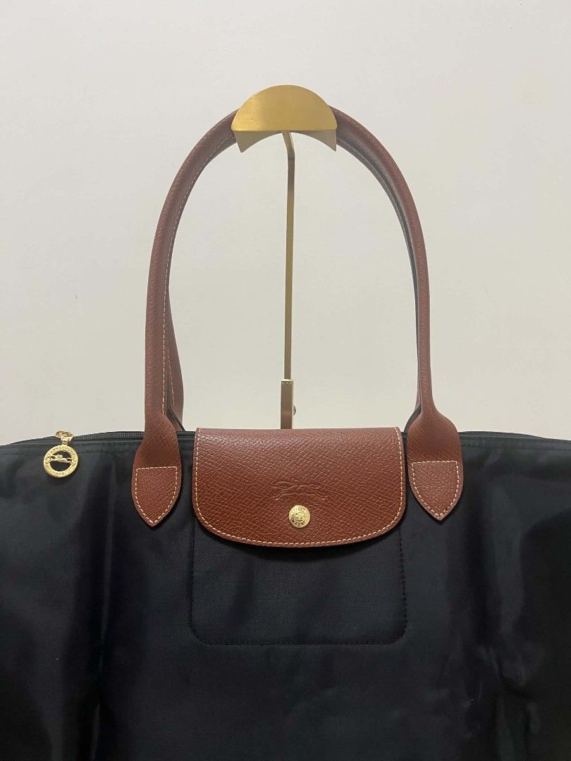 Longchamp Le Pliage Nylon Tote Bag Noir (Category: Tote Bags) located in Paoay. Submitted by rvf1230 (Listing ID 1467242571, Image 2). Description: - Authentic Longchamp Le Pliage tote bag - Color: Classic black nylon with brown leather handles and flap - Hardware: Gold-tone zipper pull with iconic jockey logo and 1948 branding - Closure: Snap button and zipper closure - Interior: Roomy and spacious, ideal for daily essentials, work, or travel - 
