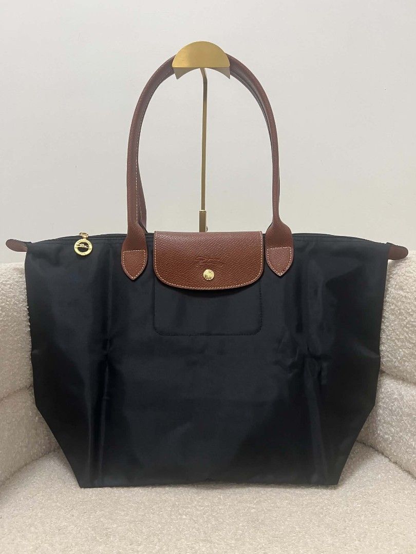 Longchamp Le Pliage Nylon Tote Bag Noir (Category: Tote Bags) located in Paoay. Submitted by rvf1230 (Listing ID 1467242571, Image 3). Description: - Authentic Longchamp Le Pliage tote bag - Color: Classic black nylon with brown leather handles and flap - Hardware: Gold-tone zipper pull with iconic jockey logo and 1948 branding - Closure: Snap button and zipper closure - Interior: Roomy and spacious, ideal for daily essentials, work, or travel - 