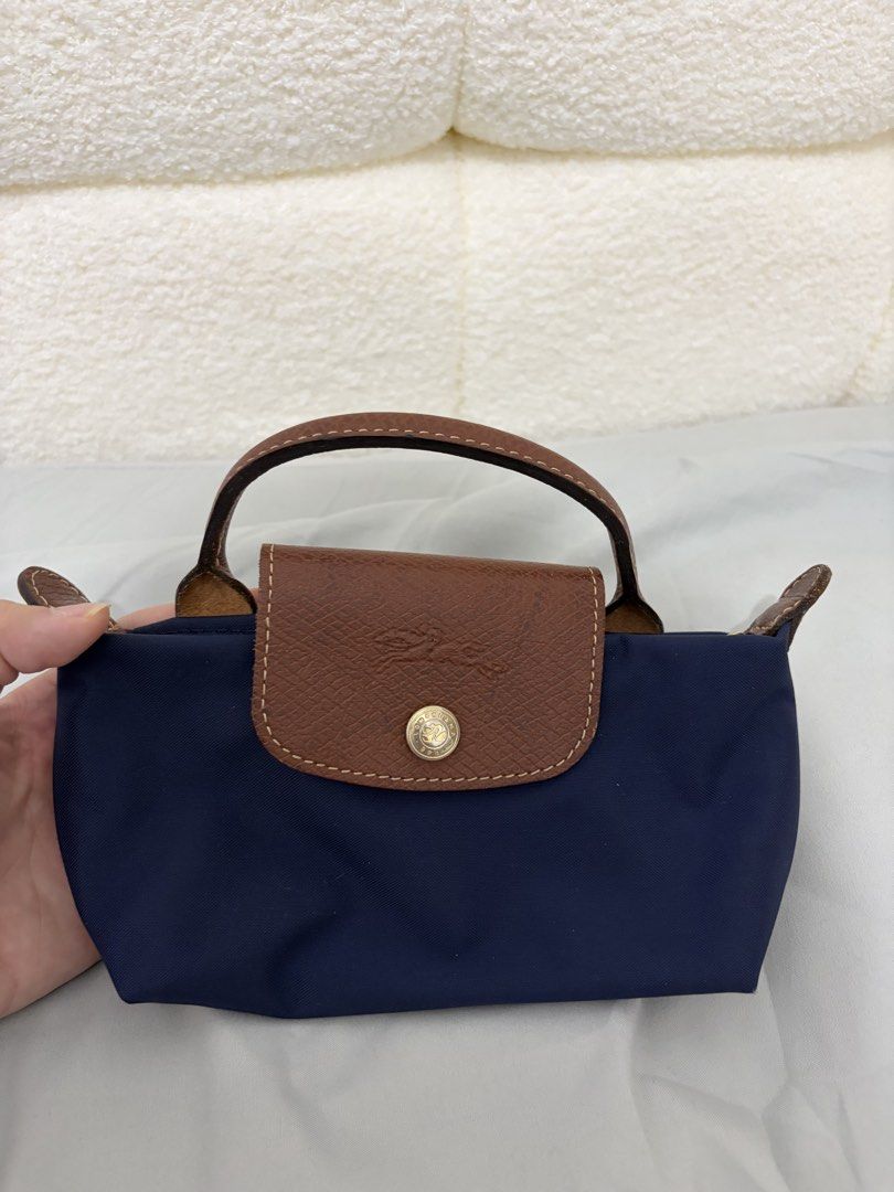 Longchamp Navy Blue Mini Handbag (Category: Luxury Bags & Wallets) located in Pasig City. Submitted by lovepinkyy (Listing ID 1467227244, Image 1). Description: - Authentic Longchamp mini handbag - Color: Navy blue with signature brown leather flap and snap button closure - Hardware: Gold tone - Origin: Made in Tunisia (with inside tag, serial, and care symbols) - Size: Compact, ideal for daily essentials and quick errands - Condition: Excellent,