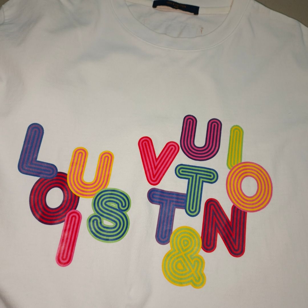 Louis Vuitton Multi-Color Graphic Tee White (Category: Tshirts & Polo Shirts ) located in Antipolo. Submitted by swift.cocopasion (Listing ID 1467286214, Image 2). Description: - Brand: Louis Vuitton - Item: White short-sleeve crewneck t-shirt - Design: Vibrant multi-colored graphic text on the front - Details: Branded blue neck tag with orange text, complete with interior size and care tags - Condition: Clean white fabric with neat stitching - S