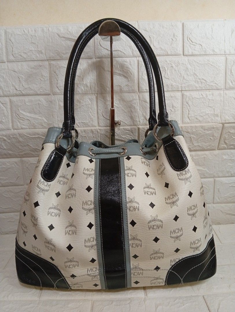 MCM Monogram Print Shoulder Bag Bucket Bag (Category: Shoulder Bags) located in Las Pinas. Submitted by etoksi1234 (Listing ID 1467224338, Image 2). Description: Pre-loved MCM monogram white tote bag with black and grey leather accents, dual top handles, and a secure drawstring closure. Features a spacious interior and structured base—perfect for daily use or travel..
