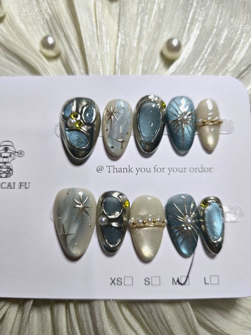 Medium Short Almond Blue and silver celestial press-on nail set (Category: Hands & Nails) located in Makati City. Submitted by jangmiscloset (Listing ID 1467315967, Image 3). Description: Double the glam, get a bonus! Buy any 2 sets (₱200 and up ) and receive a ₱100 nail set FREE. Mix & match your faves and enjoy more styles without spending extra ✨Design: Blue and cream shades with celestial star details, rhinestones, pearl accents, and metallic