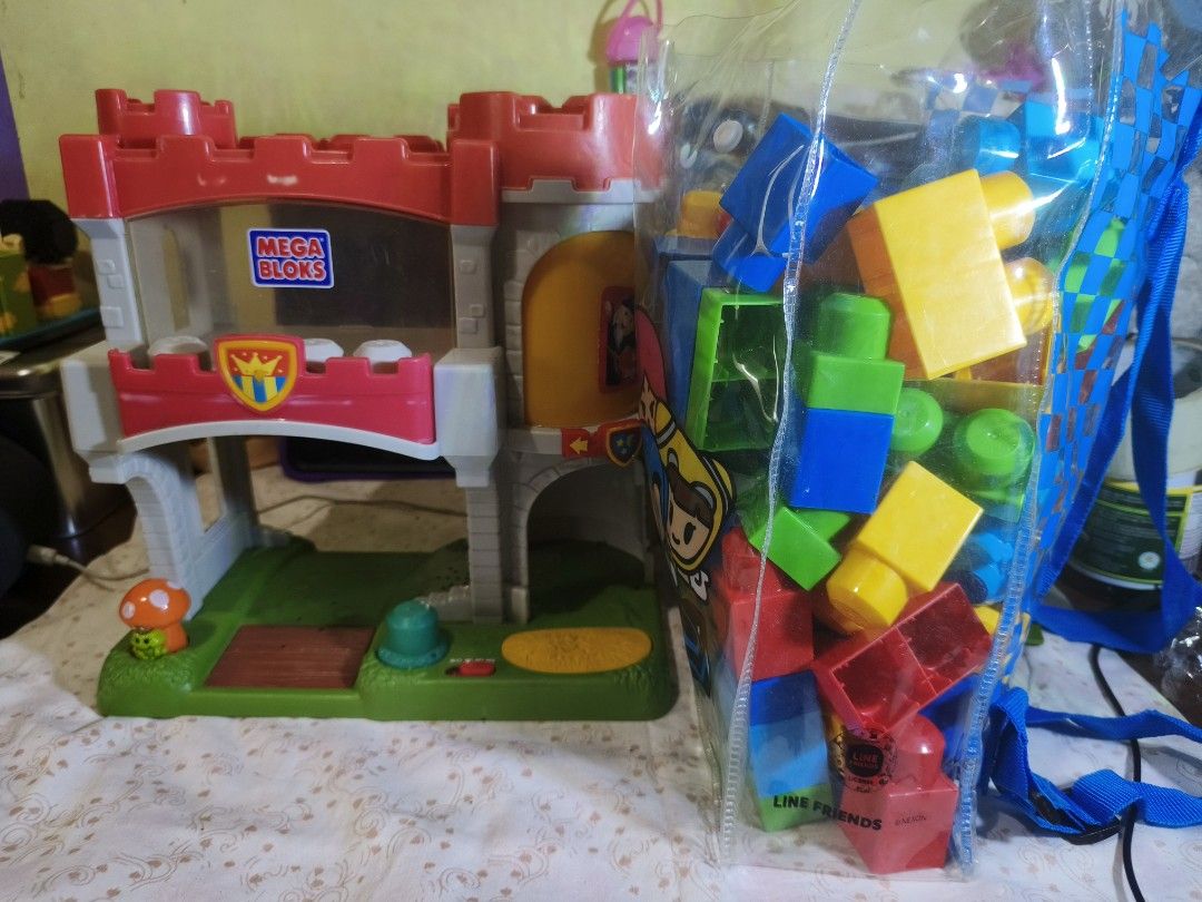 Mega Bloks Castle Play Set with Building Blocks (Category: Lego & Building Sets) located in Caloocan City. Submitted by mckysprelove (Listing ID 1467232388, Image 1). Description: Mega Bloks castle playset with a green base and red towers. Clear window panel on the front. Includes a clear plastic carrying bag filled with colorful building blocks in blue, yellow, green, and red. Great toy set for kids. this is preloved manage your expectations. lo