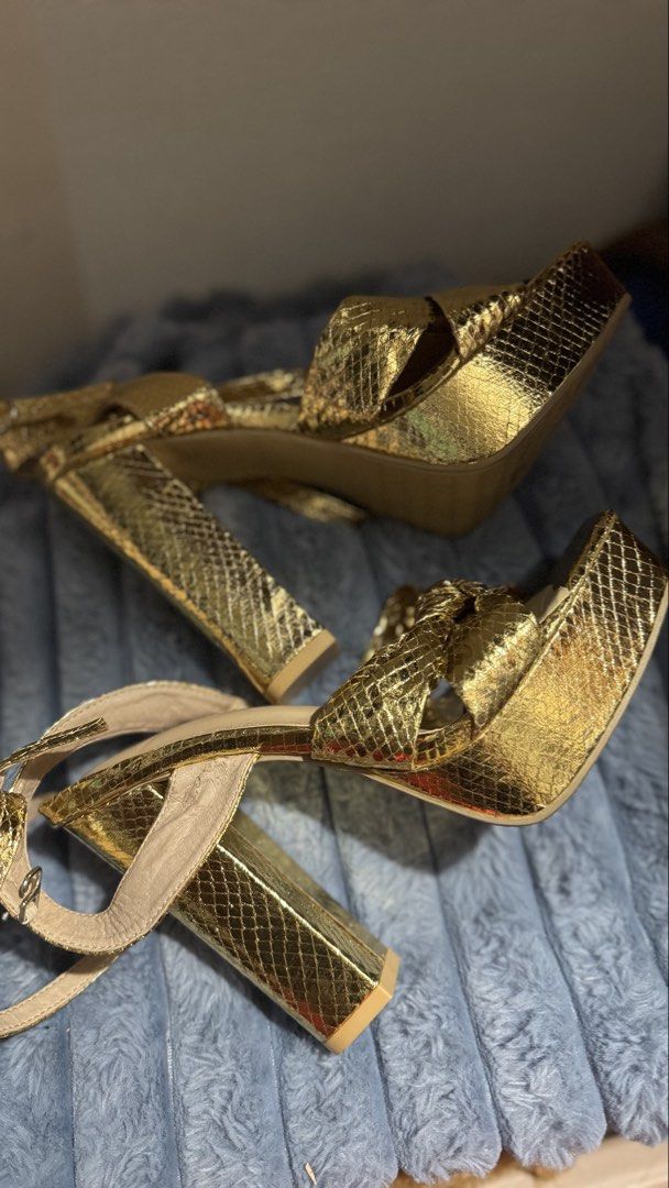 Metallic Gold Snake Print Platform Block Heels (Category: Heels) located in Manila. Submitted by darslovesfoods (Listing ID 1467189437, Image 2). Description: - Color & Texture: Metallic gold with a chic snakeskin finish - Heel & Sole: Comfortable chunky block heel with a supportive platform sole - Design: Stylish square toe with an adorable front knot detail - Closure: Adjustable ankle strap with buckle - Condition: Light wear on the bottom sole