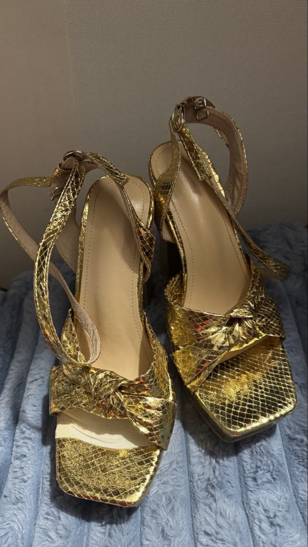 Metallic Gold Snake Print Platform Block Heels (Category: Heels) located in Manila. Submitted by darslovesfoods (Listing ID 1467189437, Image 1). Description: - Color & Texture: Metallic gold with a chic snakeskin finish - Heel & Sole: Comfortable chunky block heel with a supportive platform sole - Design: Stylish square toe with an adorable front knot detail - Closure: Adjustable ankle strap with buckle - Condition: Light wear on the bottom sole