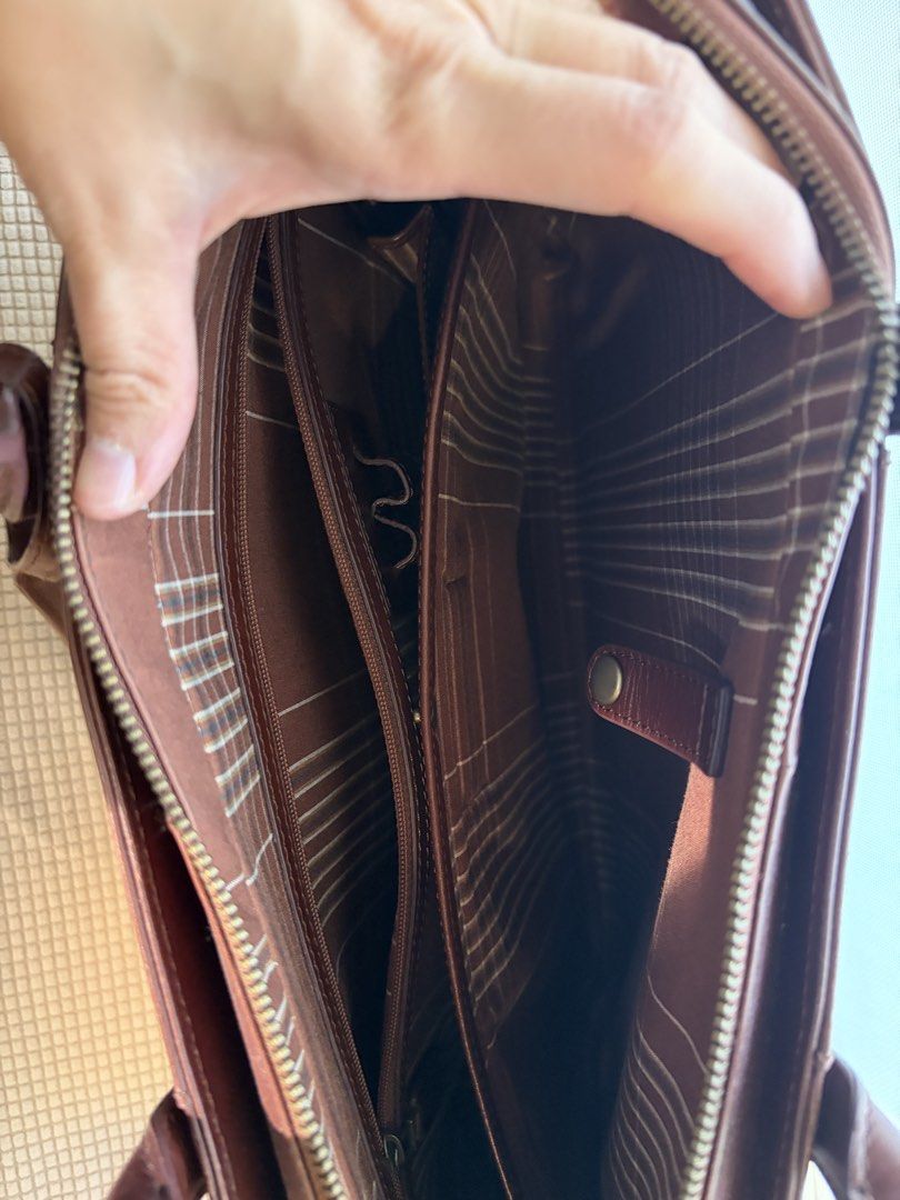 Motherhouse Brown Leather Briefcase Work Bag (Category: Briefcases) located in Taguig. Submitted by ellejay8 (Listing ID 1467245102, Image 3). Description: - Brand/Model: Motherhouse leather briefcase - Color: Rich brown - Material: Sturdy leather with structured silhouette - Interior: Striped fabric lining, multiple compartments, zipped pockets, and pen holders - Closure: Secure main zip closure - Extra Feature: Metal ring attachment on the side
