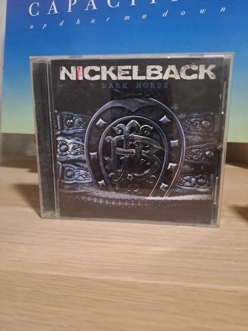 Nickelback Dark Horse CD Album (Category: CDs & DVDs) located in Las Pinas. Submitted by cobieshop (Listing ID 1467330419, Image 1). Description: - Album: Nickelback - Dark Horse - Format: Audio CD in standard plastic jewel case - Artwork: Iconic horseshoe cover featuring band name - Condition: Minor surface scuffs on the case from storage; disc is clean and ready to play - Genre: Classic rock / Alternative rock.