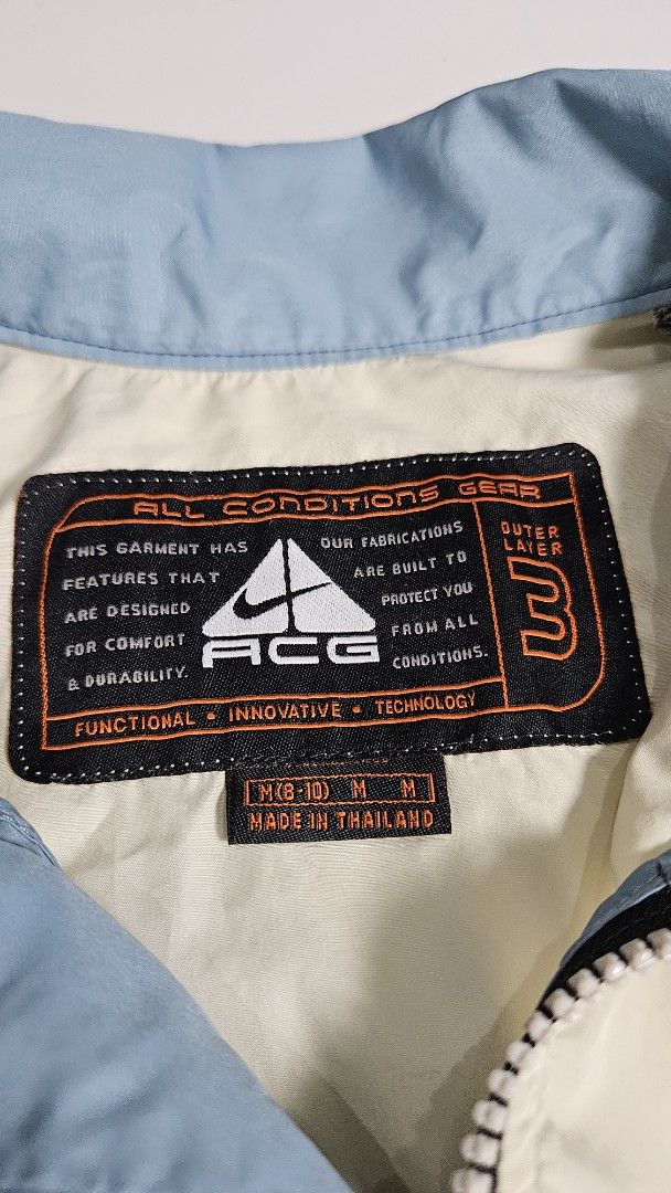Nike ACG Outer Layer 3 Windbreaker Jacket (Category: Coats, Jackets and Outerwear) located in Alfonso. Submitted by jbcamet (Listing ID 1467326149, Image 2). Description: - Brand: Nike ACG - Style: Outer layer 3-zip jacket - Color: Cream body with blue sleeves and collar - Details: Embroidered chest swoosh, Nike Fit cuff label, mesh inner lining with iconic ACG triangle logo - Size: Medium (fits US 8-10) - Origin: Made in Thailand - Condition: Ex