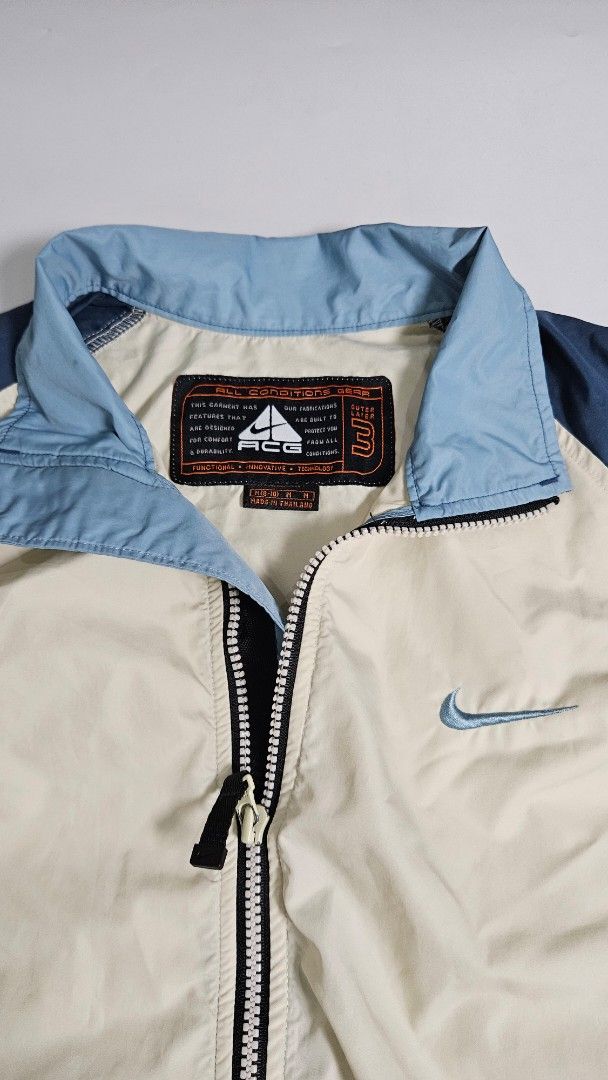 Nike ACG Outer Layer 3 Windbreaker Jacket (Category: Coats, Jackets and Outerwear) located in Alfonso. Submitted by jbcamet (Listing ID 1467326149, Image 1). Description: - Brand: Nike ACG - Style: Outer layer 3-zip jacket - Color: Cream body with blue sleeves and collar - Details: Embroidered chest swoosh, Nike Fit cuff label, mesh inner lining with iconic ACG triangle logo - Size: Medium (fits US 8-10) - Origin: Made in Thailand - Condition: Ex