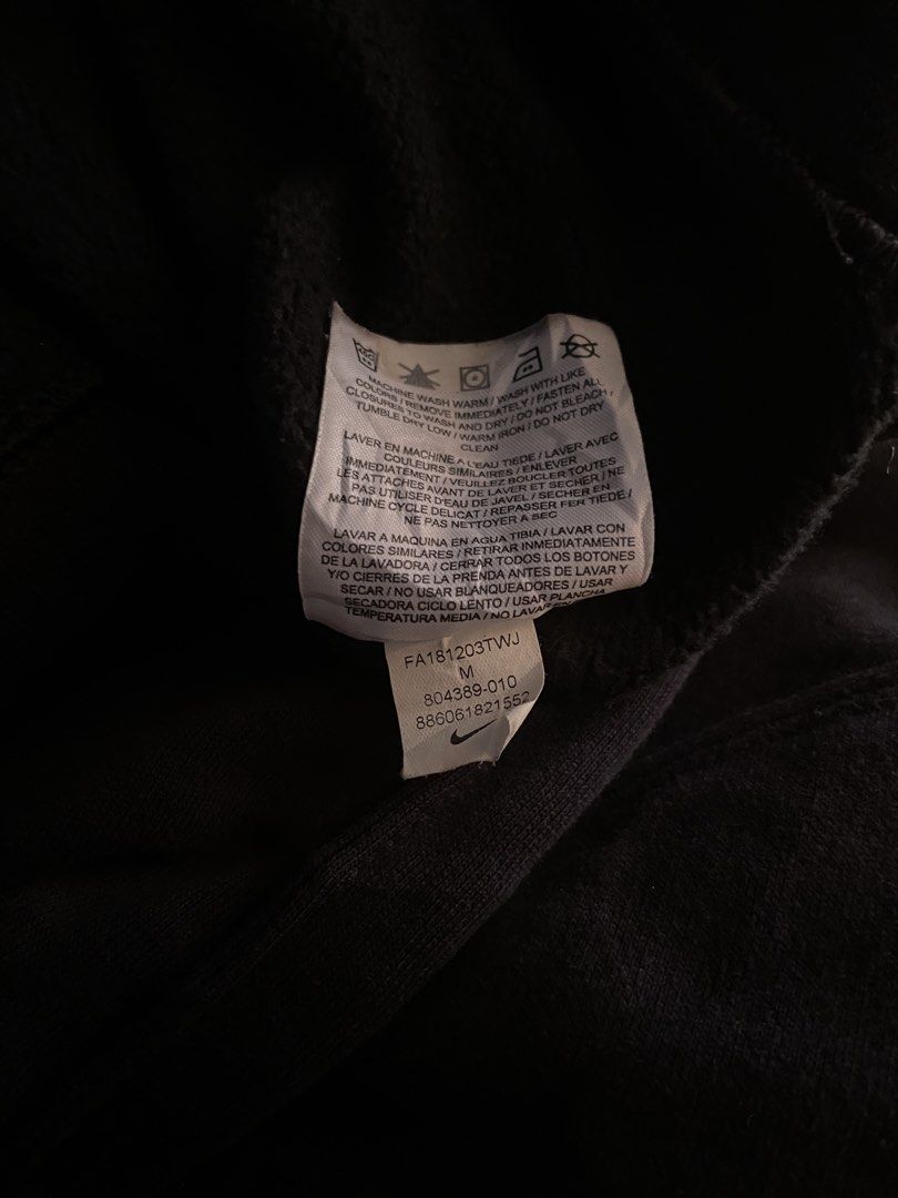 Nike Black Zip-Up Hoodie Size M (Category: Hoodies) located in Davao. Submitted by vin.my (Listing ID 1467204577, Image 3). Description: Black Nike zip-up hoodie with embroidered white logo on the chest. Full zip front, adjustable hood drawstrings, and split kangaroo pockets. Size M tag on the collar, made in Jordan. Interior care label lists style number 804389-010. Cotton blend material, comfortable everyday fit..