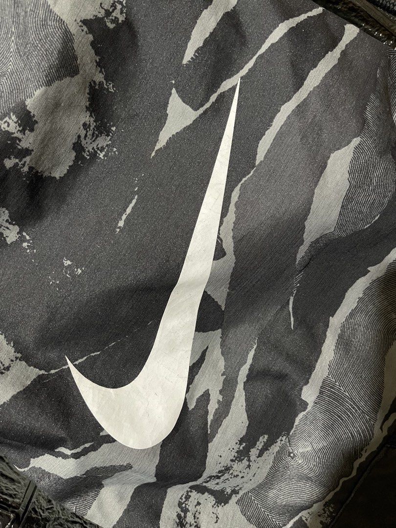 Nike Camo Gym Sack Drawstring Bag (Category: Backpacks) located in Lopez. Submitted by thrift.ni.roms22 (Listing ID 1467168273, Image 3). Description: - Brand: Nike - Item: Drawstring Gym Sack / Bag - Color/Pattern: Grey and Black Camo - Design: Large white Nike Swoosh logo on front - Storage: Front zippered pocket with Nike branded pull - Closure: Secure top drawstring - Material: 100% Polyester (Made in Indonesia) - Product Code: CU9646 010 - C