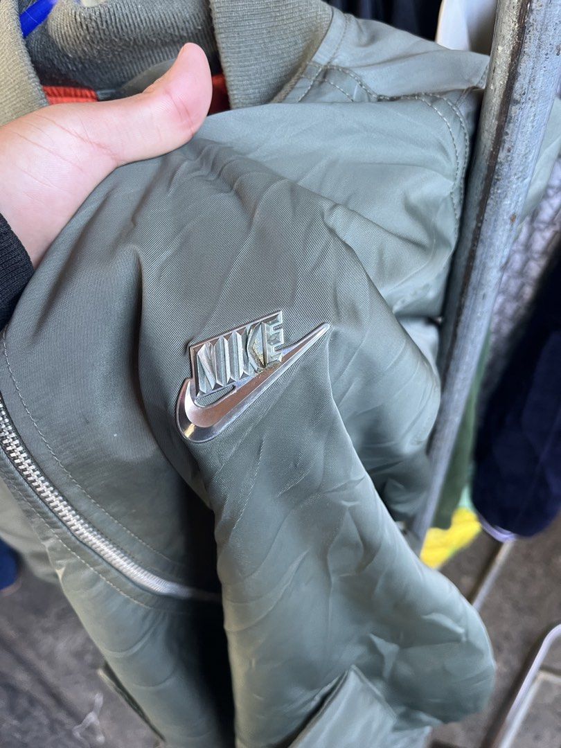Nike Green Bomber Jacket Size XL (Category: Coats, Jackets and Outerwear) located in Pontevedra. Submitted by thrift01 (Listing ID 1467262783, Image 3). Description: - Brand: Nike - Item: Bomber Jacket - Color: Green with orange interior lining - Size: XL (Standard fit) - Details: Full zip closure, metallic Nike swoosh logo on chest, large back graphic patch, and left sleeve utility pocket - Origin: Made in Vietnam - Condition: Excellent.