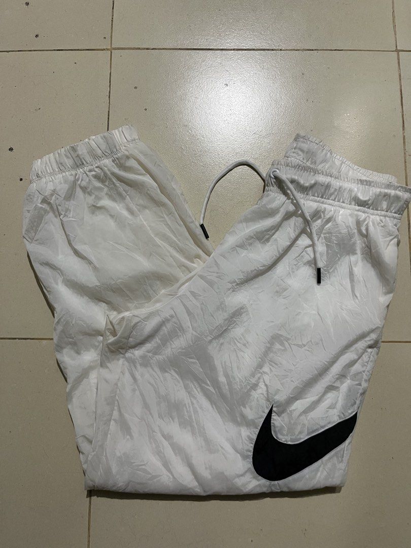 Nike White Track Pants Windrunner Joggers DM6184-100 (Category: Joggers) located in Pasay City. Submitted by Oboyyy (Listing ID 1467254155, Image 1). Description: - Brand: Nike - Item: Windrunner Track Pants - Color: White with large black Swoosh logo - Size: Medium - Product Code: DM6184-100 - Features: Elastic waistband with adjustable drawstring, inner mesh lining - Condition: Clean and ready to wear - Origin: Made in China.