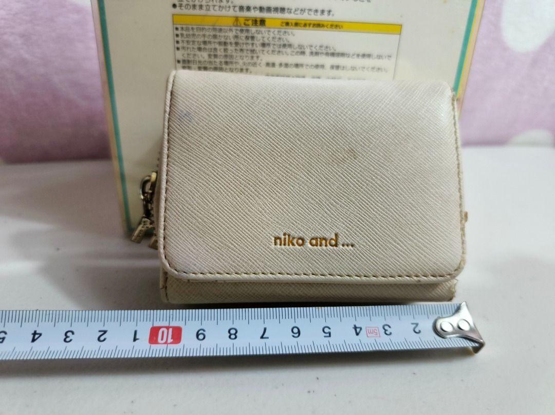 Niko and... beige trifold wallet (Category: Wallets & Card holders) located in San Leonardo. Submitted by burgossanleonardo.12345 (Listing ID 1467279410, Image 2). Description: - Brand: Niko and... - Color: Beige - Material: Textured synthetic leather with gold embossed branding - Design: Trifold wallet with a convenient side zip compartment for coins - Size: Compact, measures roughly 10cm across - Condition: Used with minor surface marks as show