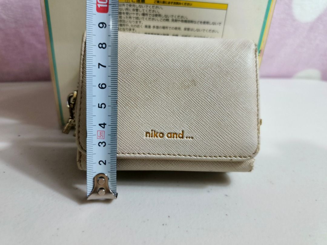 Niko and... beige trifold wallet (Category: Wallets & Card holders) located in San Leonardo. Submitted by burgossanleonardo.12345 (Listing ID 1467279410, Image 3). Description: - Brand: Niko and... - Color: Beige - Material: Textured synthetic leather with gold embossed branding - Design: Trifold wallet with a convenient side zip compartment for coins - Size: Compact, measures roughly 10cm across - Condition: Used with minor surface marks as show