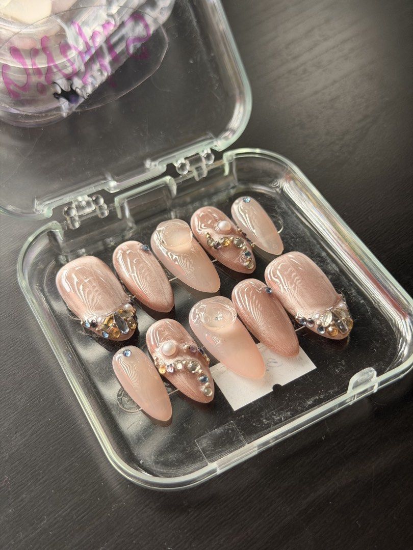 Nude Rhinestone Pearl Custom Press-On Nails Set (SIZE M) (Category: Hands & Nails) located in Quezon City. Submitted by ninny.ph (Listing ID 1467190459, Image 2). Description: - Design: Neutral nude cat-eye finish with rhinestones, pearls, and 3D textured gel art - Shape & Length: Almond shape, ready-to-wear handmade set - Inclusion: 10 pieces of press-on nails - Packaging: Comes in a convenient clear plastic carrying case - Note: Adhesive not in