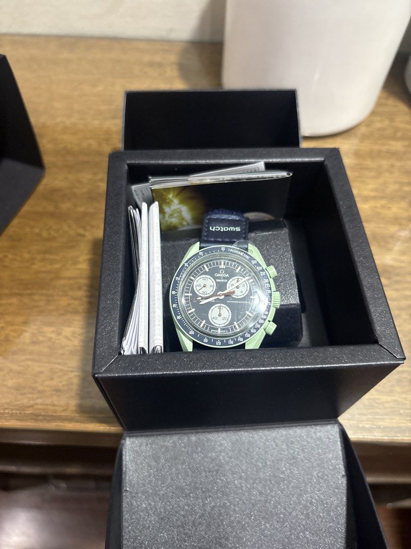 OMEGA X SWATCH MOONSWATCH (Category: Men's Watches) located in Paranaque City. Submitted by corinne_see (Listing ID 1467308904, Image 2). Description: - Brand: Omega x Swatch Bioceramic MoonSwatch - Condition: Brand new, never worn, fresh out of the packaging with crystal protective sticker still attached - Colors: Dark dial with white subdials, light green case, and blue fabric strap - Features: Fully functional chronograph - Inclusions: Complet