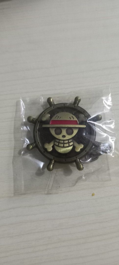 One Piece Luffy Pirate Ship Wheel Keychain (Category: Character Goods) located in Pasig City. Submitted by j-fri0127 (Listing ID 1467176628, Image 1). Description: - Official One Piece design: Ship's steering wheel with Luffy's iconic straw hat skull emblem in the center - Premium look: Detailed metalwork with a stylish antique bronze finish - Brand new: Still sealed in original clear plastic packaging - Versatile: Great for anime merch collector