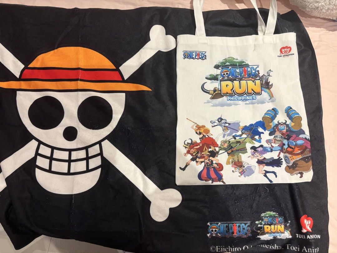 One Piece Run Philippines Tote Bag and Towel Set (Category: Tote Bags) located in Quezon City. Submitted by kindakristelle2481 (Listing ID 1467200061, Image 1). Description: - Official One Piece Run Philippines merchandise bundle - 1x White canvas tote bag with Straw Hat crew graphics - 1x Large black beach towel featuring the Jolly Roger logo - Authentic Toei Animation copyright markings printed at the bottom - Clean fabrics and vibrant prints, 