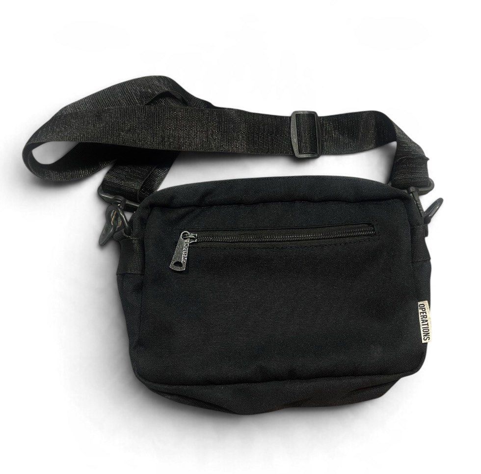 Operations Black Multi-Compartment Canvas Crossbody Bag Unisex (Category: Cross-body Bags) located in San Pedro. Submitted by lifebeginsaftercoff33 (Listing ID 1467081066, Image 3). Description: - Brand: Operations - Color: Black - Material: Durable canvas fabric - Storage: Multiple zippered compartments inside and out - Strap: Adjustable shoulder strap with sturdy clips - Condition/Details: Clean interior lining with front brand patch and intern