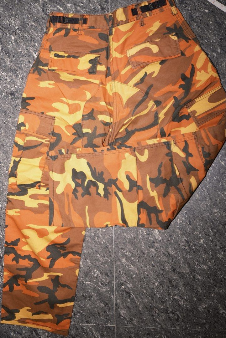 Orange Camo Cargo Pants Utility Trousers (Category: Joggers) located in Guiguinto. Submitted by aries_ji (Listing ID 1467250008, Image 2). Description: - Vibrant orange and yellow camouflage design - Multiple utility pockets on sides and back - Adjustable back straps on the waistband for a custom fit - Secure button closure and zip fly - Comfortable cotton blend material - Classic straight leg cut.