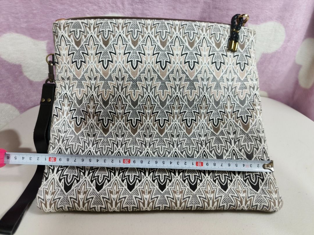 Patterned Fabric Clutch Handbag with Wrist Strap (Category: Clutches) located in San Leonardo. Submitted by burgossanleonardo.12345 (Listing ID 1467278428, Image 3). Description: - Style: Textured clutch bag with a geometric zig-zag pattern - Colors: Black, white, and tan - Dimensions: Approx. 33 cm (width) x 28 cm (height) - Strap: Dark leather wrist strap (approx. 17 cm) - Closure: Secure top zipper - Condition: Clean inside and out, ready to u