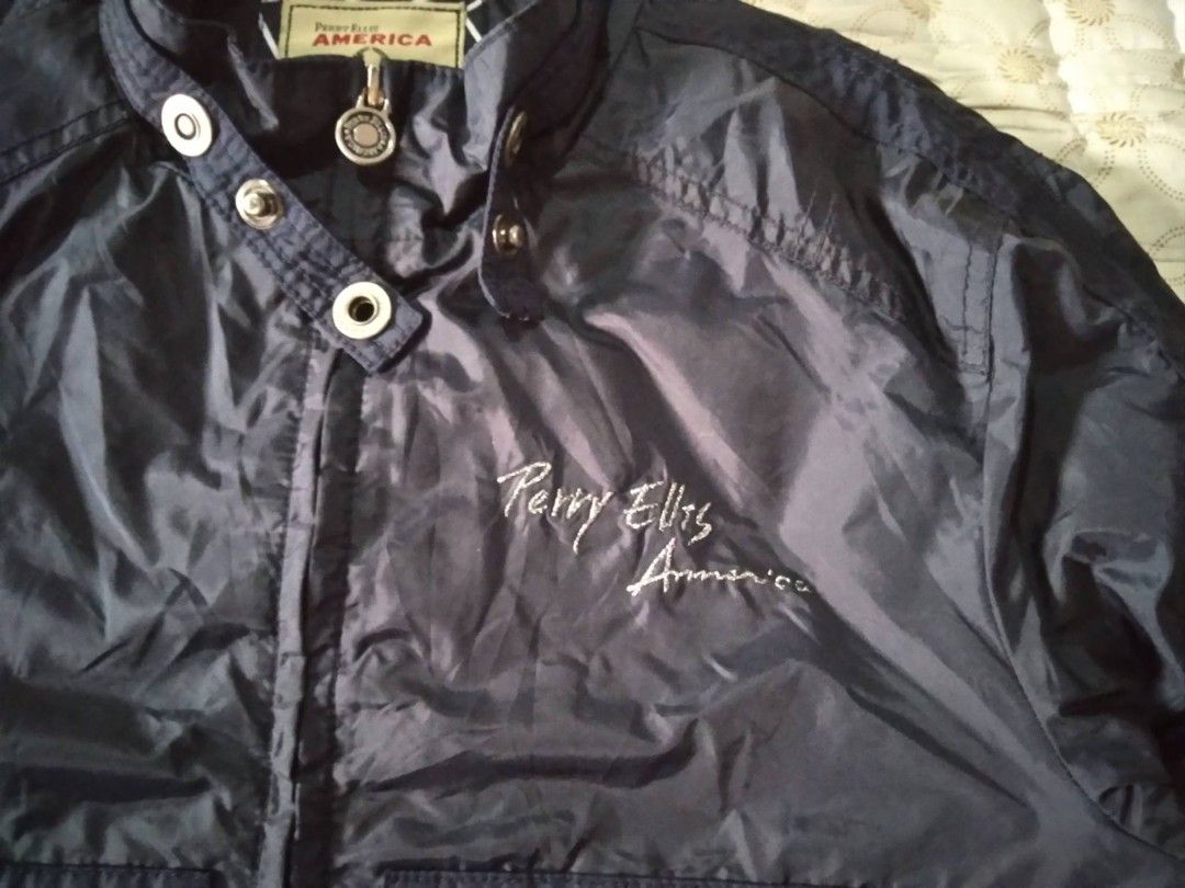 Perry Ellis America Navy Blue Zip Jacket (Category: Coats, Jackets and Outerwear) located in Zamboanga. Submitted by nurbya898048 (Listing ID 1467249864, Image 2). Description: Navy blue Perry Ellis America jacket. Stand collar with snap button closure. Embroidered script logo on the chest. Full zip front with custom circular branded pull tab. Zipped pockets on both sides. Ribbed hem and cuffs. Contrast yellow trim on the inner lining and striped