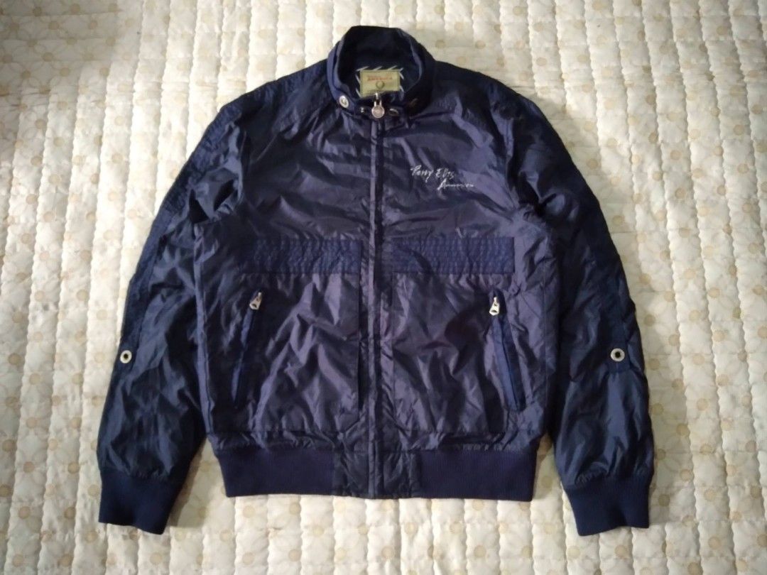 Perry Ellis America Navy Blue Zip Jacket (Category: Coats, Jackets and Outerwear) located in Zamboanga. Submitted by nurbya898048 (Listing ID 1467249864, Image 1). Description: Navy blue Perry Ellis America jacket. Stand collar with snap button closure. Embroidered script logo on the chest. Full zip front with custom circular branded pull tab. Zipped pockets on both sides. Ribbed hem and cuffs. Contrast yellow trim on the inner lining and striped