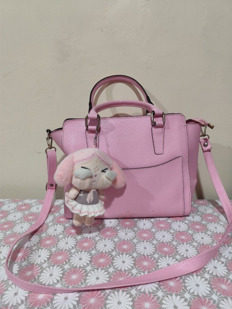 Pink handbag with plush charm (Category: Shoulder Bags) located in Naga. Submitted by semflewer (Listing ID 1467345344, Image 3). Description: - Color: Bright pink - Style: Structured handbag with top handles and adjustable shoulder strap - Includes: Adorable removable pink bunny plush keychain - Interior: Multiple compartments with a secure middle zip pocket - Protection: Metal feet on the bottom to prevent scuffs - Condition: Clean interior lin