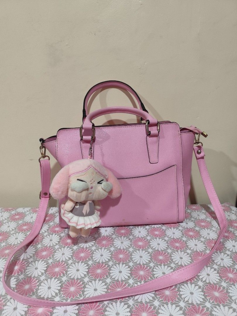 Pink handbag with plush charm (Category: Shoulder Bags) located in Naga. Submitted by semflewer (Listing ID 1467345344, Image 2). Description: - Color: Bright pink - Style: Structured handbag with top handles and adjustable shoulder strap - Includes: Adorable removable pink bunny plush keychain - Interior: Multiple compartments with a secure middle zip pocket - Protection: Metal feet on the bottom to prevent scuffs - Condition: Clean interior lin