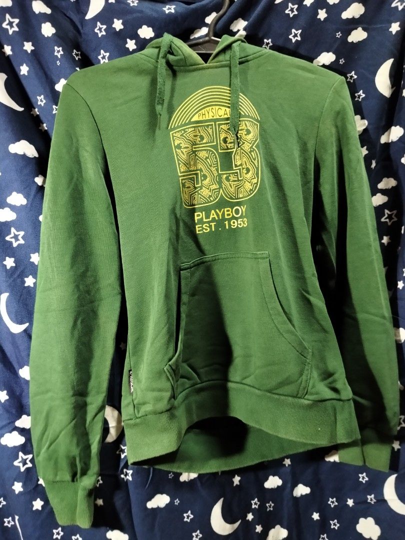 Playboy Physical Green Hoodie (Category: Coats, Jackets and Outerwear) located in Manila. Submitted by tawnycollectiblesshop (Listing ID 1467218930, Image 1). Description: - Size: Fits Medium - Color: Green with contrasting yellow patterned hood lining - Design: Large front graphic print with '53' and Playboy branding, plus extra logo detail on the lower back - Features: Practical kangaroo pocket, ribbed cuffs, and hem - Condition: Pre-loved, wel