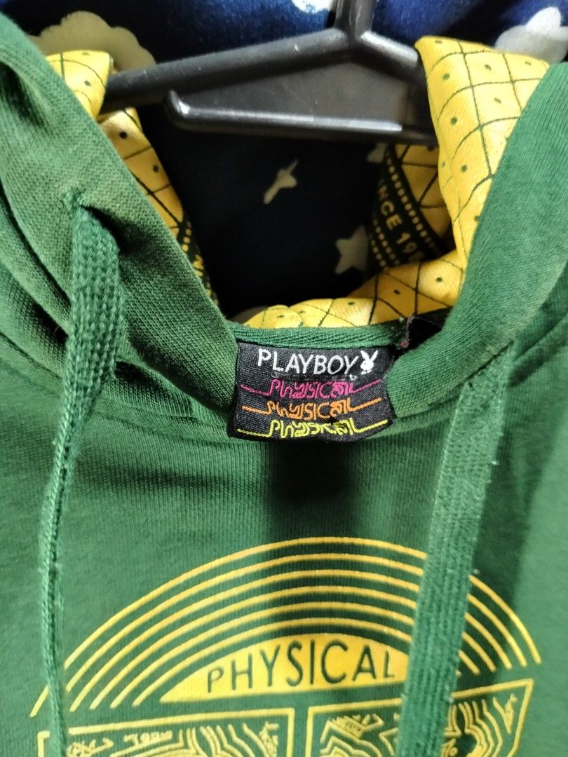 Playboy Physical Green Hoodie (Category: Coats, Jackets and Outerwear) located in Manila. Submitted by tawnycollectiblesshop (Listing ID 1467218930, Image 2). Description: - Size: Fits Medium - Color: Green with contrasting yellow patterned hood lining - Design: Large front graphic print with '53' and Playboy branding, plus extra logo detail on the lower back - Features: Practical kangaroo pocket, ribbed cuffs, and hem - Condition: Pre-loved, wel