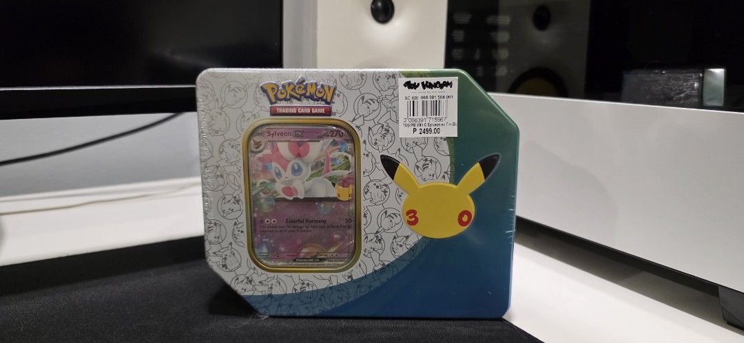 Pokémon 30th Celebration Tin English (Category: Card Boxes & Cases) located in San Juan City. Submitted by SoleTech_Manila (Listing ID 1467297944, Image 1). Description: - Factory-sealed Pokémon 30th Celebration tin featuring Sylveon ex - Pristine, unopened condition with original plastic wrap intact - Includes 1 exclusive foil promo card of Sylveon ex - Comes with 5 Pokémon TCG 30th Celebration booster packs - Perfect addition for TCG collectors