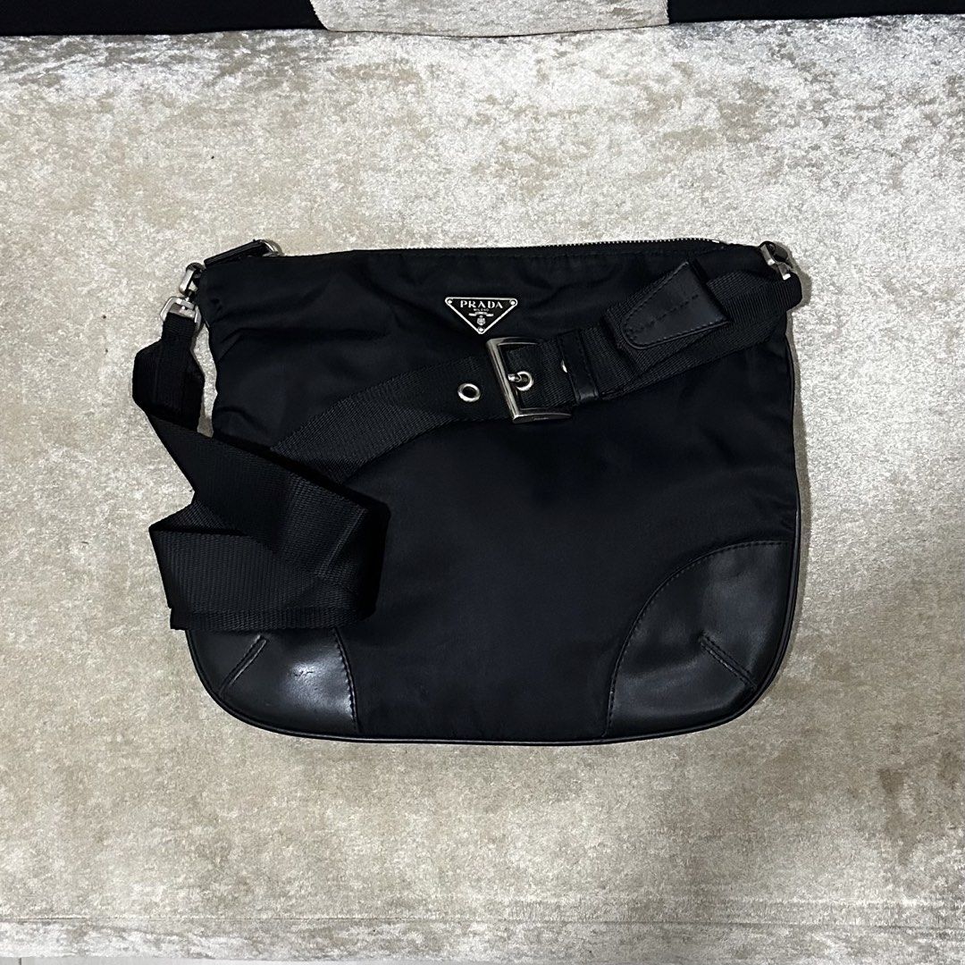 Prada Black Nylon Crossbody Bag (Category: Luxury Bags & Wallets) located in Quezon City. Submitted by retroboominwantsummoh (Listing ID 1467335168, Image 3). Description: - Authentic Prada crossbody bag - Durable black nylon material with leather corner reinforcements - Classic silver-tone metal hardware - Iconic triangular Prada metal logo plaque on the front - Secure zip top closure - Adjustable black fabric shoulder strap - Clean interior and