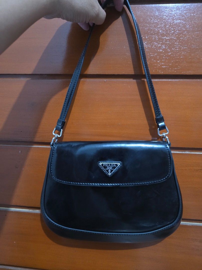 Prada Black Patent Leather Shoulder Bag (Category: Luxury Bags & Wallets) located in Lemery. Submitted by venus23 (Listing ID 1467191129, Image 1). Description: - Brand: Prada - Material: Black patent leather with glossy finish - Hardware & Logo: Silver-tone hardware with classic triangle logo plaque - Closure: Flap closure - Interior: Clean dark lining with enough room for daily essentials - Condition: Excellent/Classic piece.