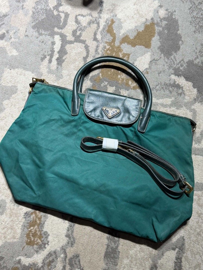 Prada Green Nylon with sling Tote Bag (Category: Luxury Bags & Wallets) located in Dagupan City. Submitted by kiroshi12 (Listing ID 1467238437, Image 1). Description: - Authentic Green Prada Tote Bag - Durable nylon material with chic leather handles - Front flap pocket featuring the iconic Prada triangle logo plaque - Premium gold-tone hardware and secure top zip closure with riri zipper - Includes a matching detachable shoulder strap (still wra