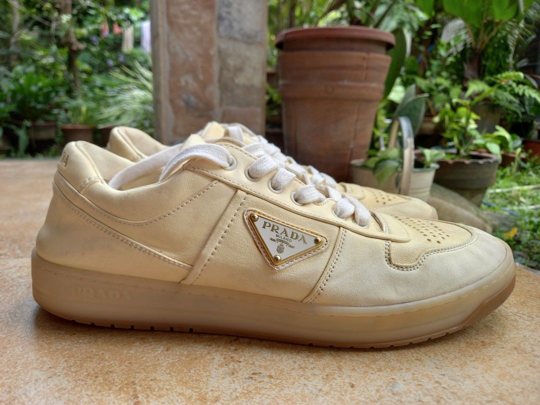 Prada Leather Sneakers Yellow (Category: Sneakers) located in Davao. Submitted by kirk214red-50020 (Listing ID 1467181967, Image 3). Description: - Brand: Prada - Color: Pale yellow with white laces - Material: Premium leather upper - Design: Low-top with perforated toe box and chunky translucent rubber sole - Branding: Iconic enamel triangle logo on the side and embossed lettering on the heel - Style: Luxury streetwear.