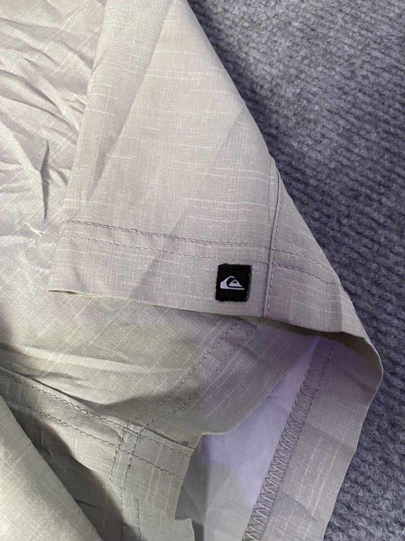 Quiksilver Men's Grey Cargo Shorts (Category: Shorts) located in Maria Aurora. Submitted by mightypenguin.f7ca53 (Listing ID 1467272287, Image 3). Description: - Brand: Quiksilver - Color: Light grey with subtle textured pattern - Closure: Button closure with belt loops - Pockets: Multiple functional pockets, including a side pocket with bungee cord loop and branded tag - Details: Quiksilver logo patch near the hem - Condition: Good casual wear o