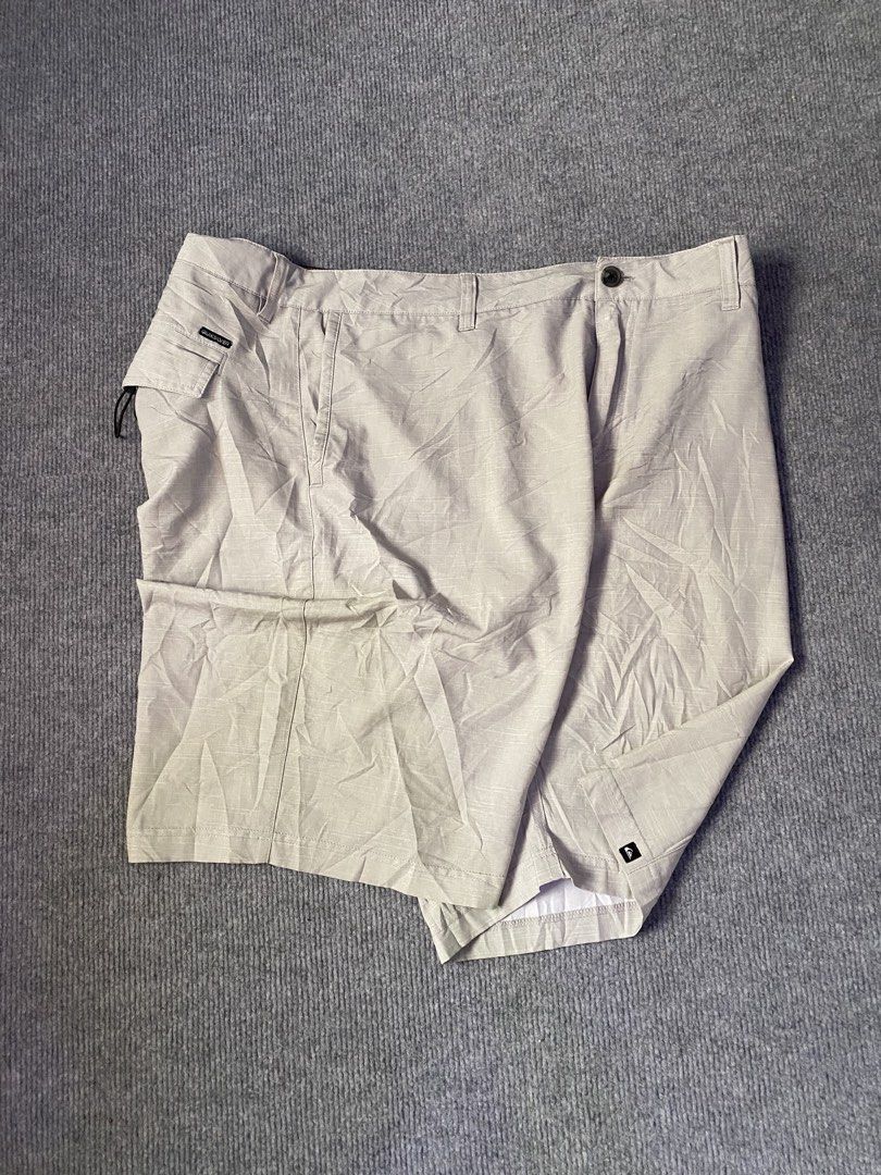 Quiksilver Men's Grey Cargo Shorts (Category: Shorts) located in Maria Aurora. Submitted by mightypenguin.f7ca53 (Listing ID 1467272287, Image 2). Description: - Brand: Quiksilver - Color: Light grey with subtle textured pattern - Closure: Button closure with belt loops - Pockets: Multiple functional pockets, including a side pocket with bungee cord loop and branded tag - Details: Quiksilver logo patch near the hem - Condition: Good casual wear o