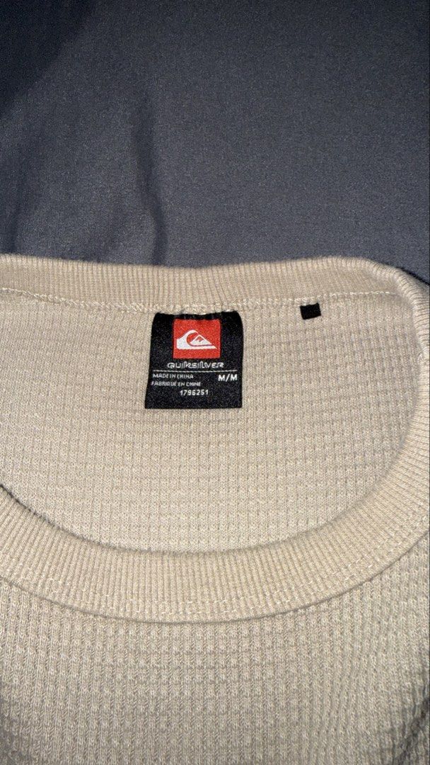 Quiksilver Waffle Knit Long Sleeve Sweater Medium (Category: Coats, Jackets and Outerwear) located in Andop. Submitted by nobleangel (Listing ID 1467310336, Image 3). Description: - Brand: Quiksilver - Color: Beige - Size: Medium - Material: Soft waffle knit textured fabric - Design: Crew neck with ribbed cuffs and hem - Details: Small embroidered mountain logo on the chest and branded tag near the lower hem - Condition/Use: Comfortable everyday 