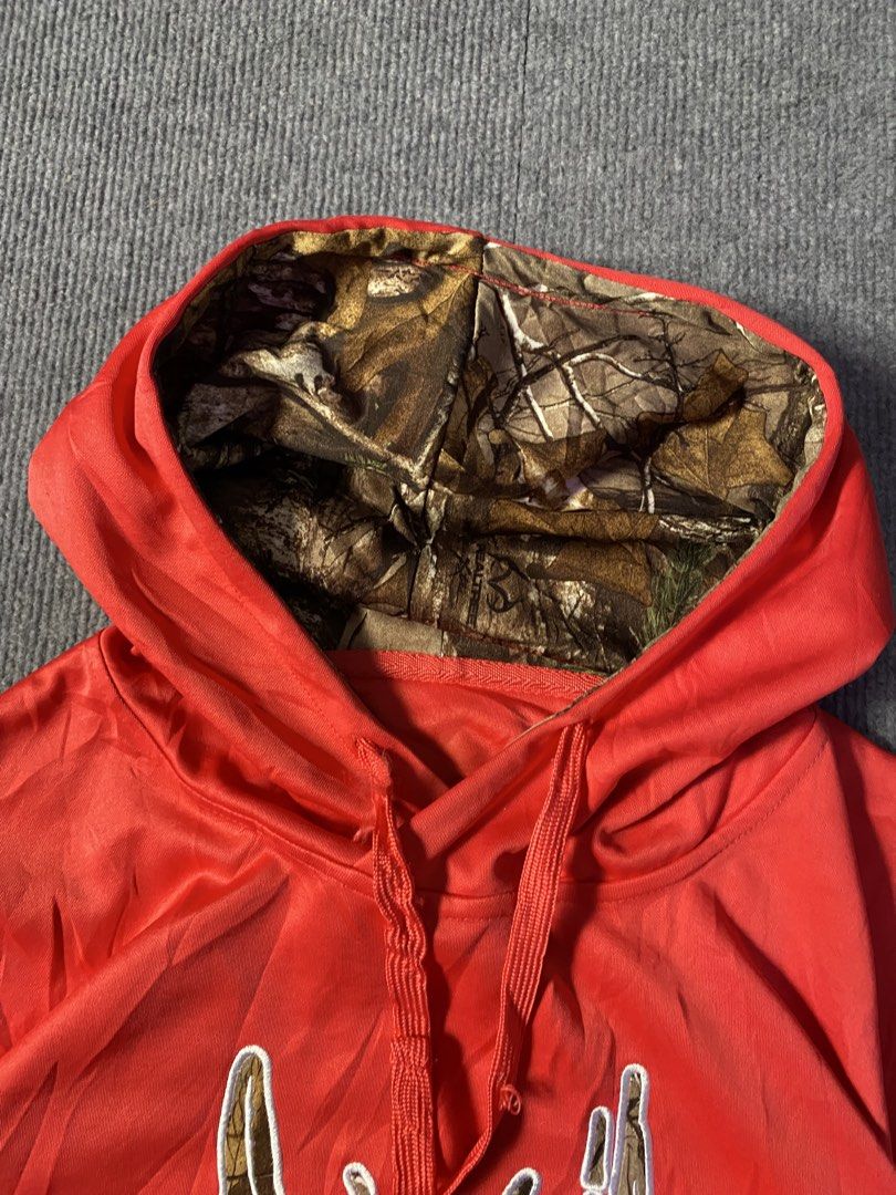 Realtree pink Camo Accent Pullover Hoodie (Category: Coats, Jackets and Outerwear) located in Maria Aurora. Submitted by mightypenguin.f7ca53 (Listing ID 1467272794, Image 3). Description: - Brand: Realtree - Color: Bright orange with camo accents - Design: Embroidered antler logo on chest, camo hood lining and pocket trims - Features: Adjustable drawstrings, front kangaroo pocket - Material: Soft fabric construction.