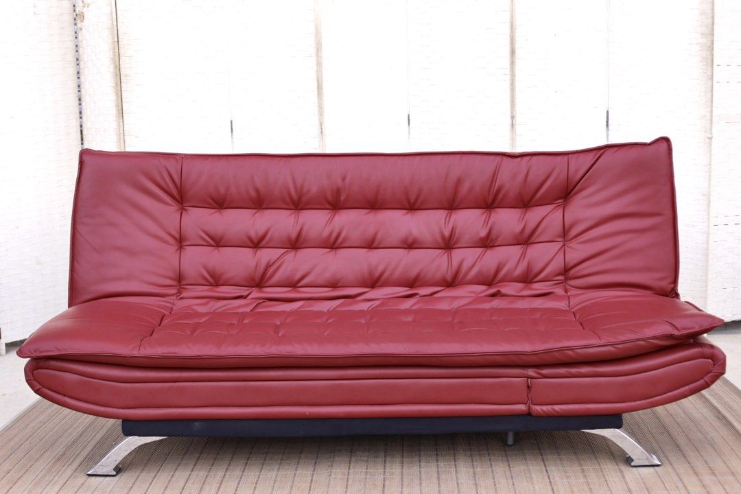 Red leather sofa bed convertible futon with chrome legs (Category: Sofas) located in Bulacan. Submitted by FurnitureGallery (Listing ID 1467302934, Image 1). Description: - Red faux leather futon sofa bed - Easily converts flat for sleeping or lounging - Comfortable tufted cushions on seat and backrest - Sleek shiny chrome metal legs - Sturdy solid frame underneath - Condition note: Has scuff marks and a small tear on the corner upholstery near t