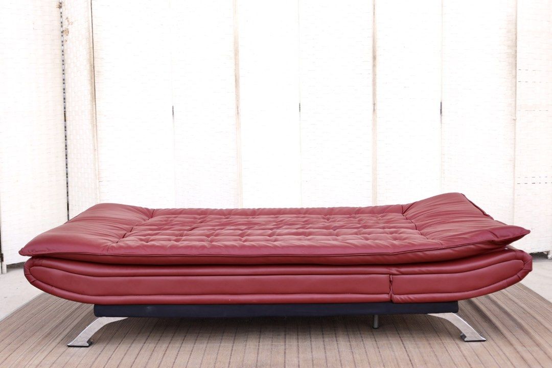 Red leather sofa bed convertible futon with chrome legs (Category: Sofas) located in Bulacan. Submitted by FurnitureGallery (Listing ID 1467302934, Image 2). Description: - Red faux leather futon sofa bed - Easily converts flat for sleeping or lounging - Comfortable tufted cushions on seat and backrest - Sleek shiny chrome metal legs - Sturdy solid frame underneath - Condition note: Has scuff marks and a small tear on the corner upholstery near t